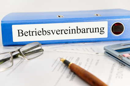Bild zeigt einen Ordner mit Aufschrift Betriebsvereinbarung, Brille, Füller und Taschenrechner